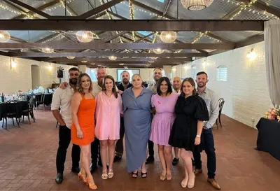 Group of people posing for a photo in a festively lit indoor venue with string lights overhead.