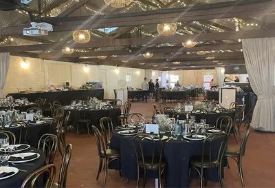 Banquet hall with round tables in navy cloths, floral centrepieces and string lights.
