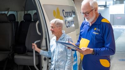 An elderly person steps into a Cancer Council van as a volunteer takes notes on a clipboard.