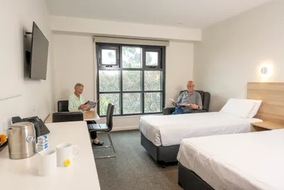 Two older people sitting and reading in guest bedroom