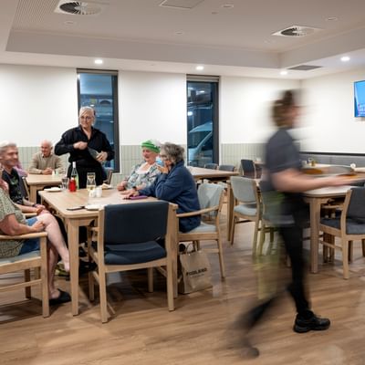 Dining room image with five at a table enjoying dinner.