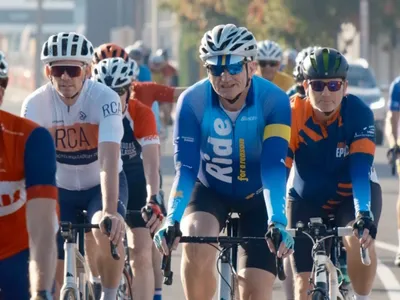 Group of cyclists in helmets riding on a city street, wearing colourful jerseys.