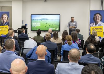 A man stands in front of a crowd of business people presenting about partnerships with Cancer Council SA