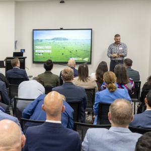 A man stands in front of a crowd of business people presenting about partnerships with Cancer Council SA