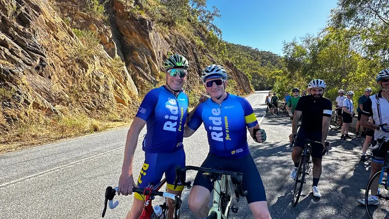 Two people on their bikes riding through the hills.