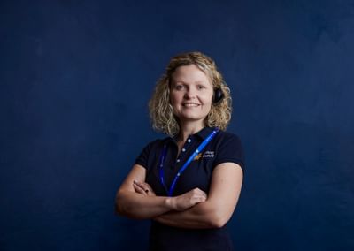 Cancer nurse standing looking at the camera wearing a headset and navy blue Cancer Council polo shirt.