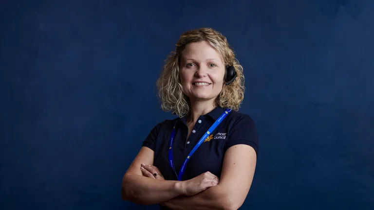 Cancer nurse standing looking at the camera wearing a headset and navy blue Cancer Council polo shirt.