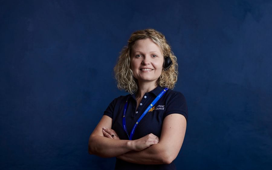 Cancer nurse standing looking at the camera wearing a headset and navy blue Cancer Council polo shirt.