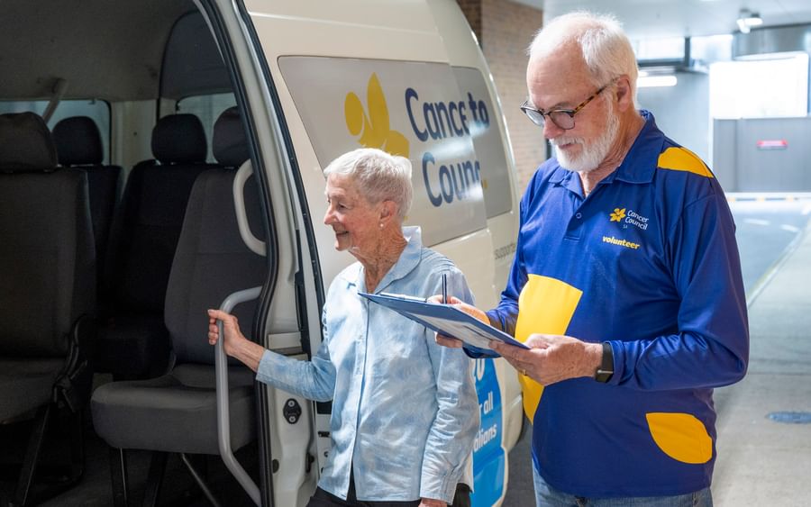Person holding clipboard welcoming another person on board a van.