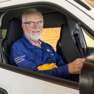 Person in drivers seat of van holding the steering wheel while looking at the camera.