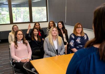 Group of people seated in a conference room listening to a speaker at a wooden table.