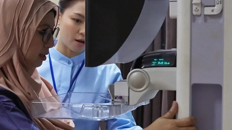 Person wearing hijab and a clinician operate a medical device with a clear tray.