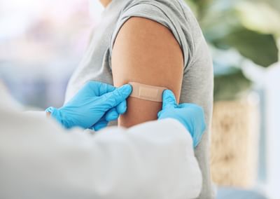 Close-up of a person’s upper arm as a clinician wearing blue gloves applies a bandage.