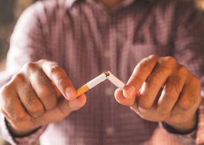Close-up of a person breaking a cigarette in half with both hands.