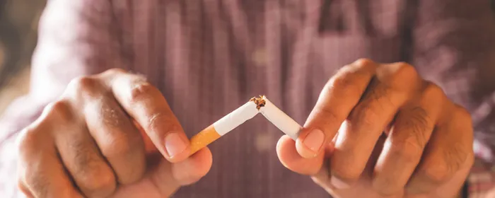 Close-up of a person breaking a cigarette in half with both hands.