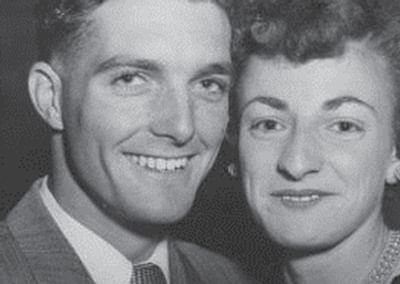 Black-and-white portrait of a smiling couple posing closely, one on the left and the other on the right.