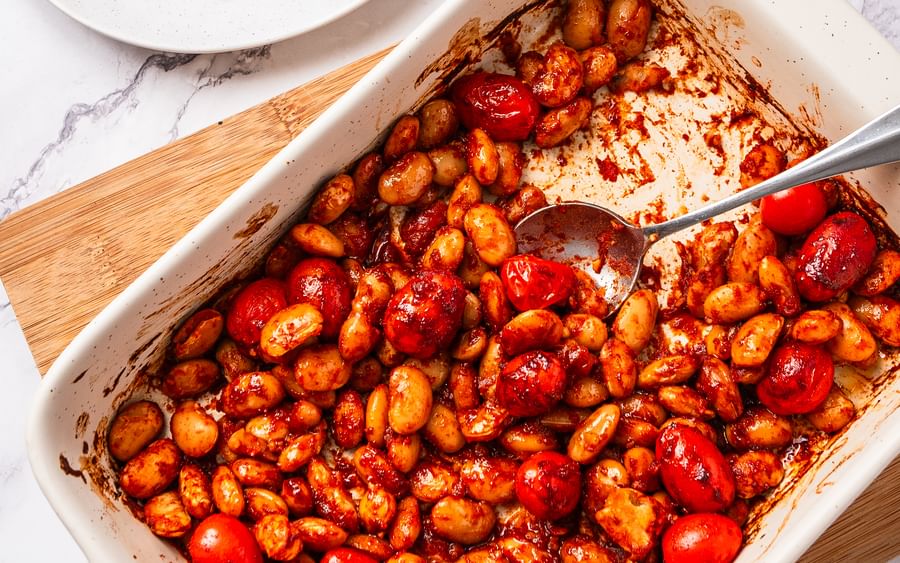 Roasted cherry tomatoes and potatoes in a white baking dish; plate of toast with tomatoes and feta.