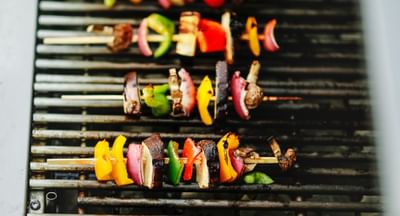Skewers of meat and colorful peppers grilling on a barbecue.