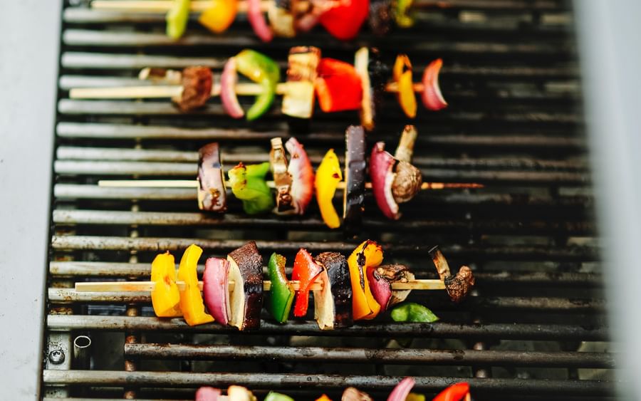 Skewers of meat and colorful peppers grilling on a barbecue.