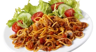 Plate of spaghetti with meat sauce and vegetables, with lettuce, cucumber and tomato garnish.