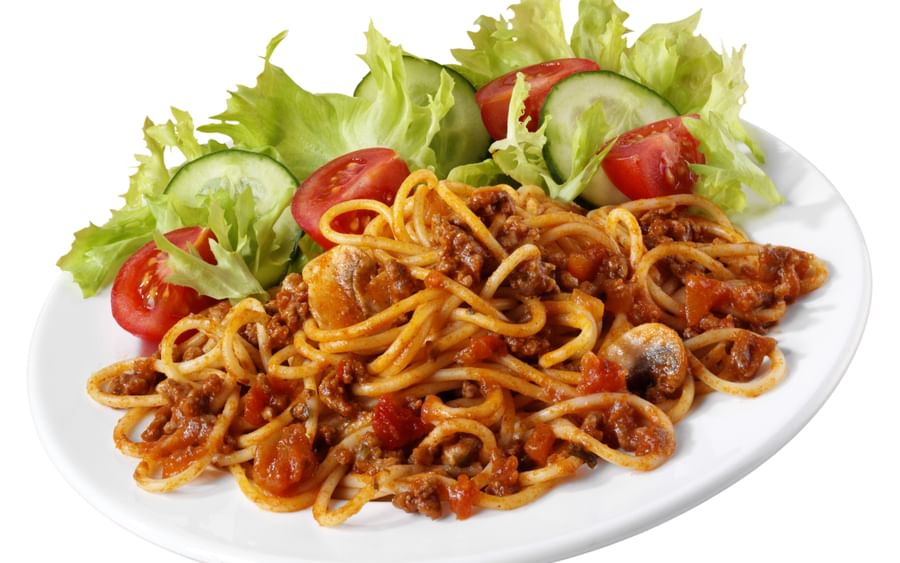 Plate of spaghetti with meat sauce and vegetables, with lettuce, cucumber and tomato garnish.