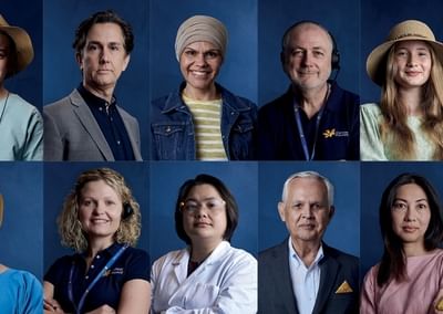 Twelve diverse professionals posed in two rows against a blue backdrop.