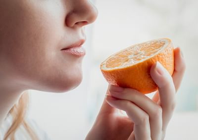 Close-up of a person holding a halved orange near their lips, about to take a bite.