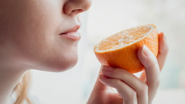 Close-up of a person holding a halved orange near their lips, about to take a bite.