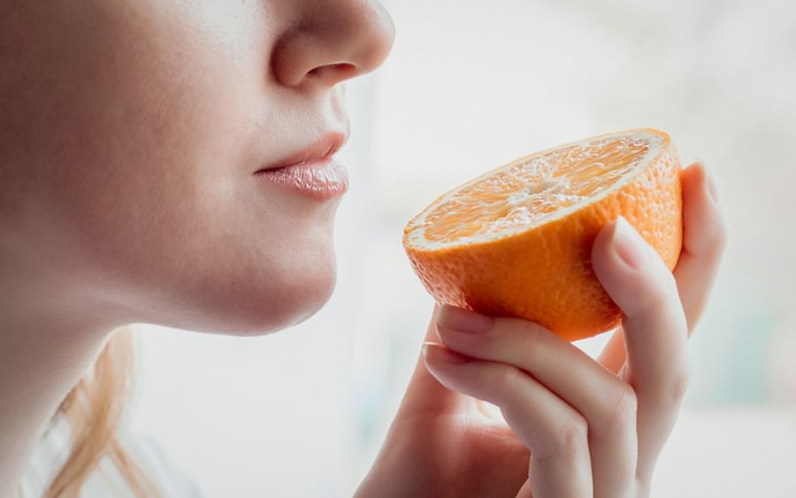 Close-up of a person holding a halved orange near their lips, about to take a bite.
