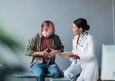 Three people sit on a sofa, examining a tablet together, against an orange wall.