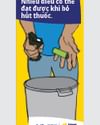Person in blue clothing places a green item into a gray trash can beneath a Vietnamese banner.