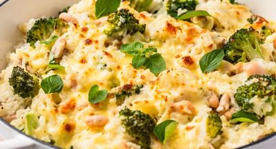A frying pan filled with a cheesy chicken and broccoli rice dish