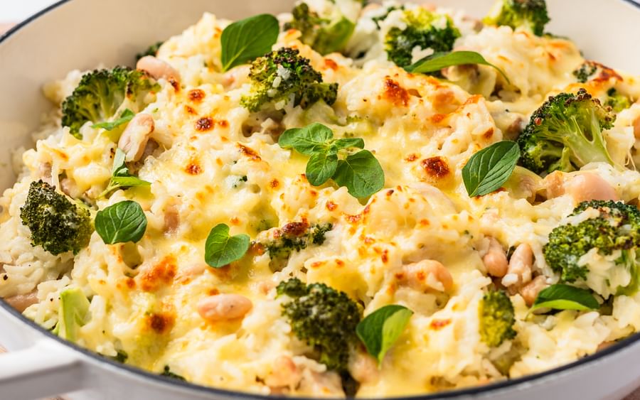 A frying pan filled with a cheesy chicken and broccoli rice dish