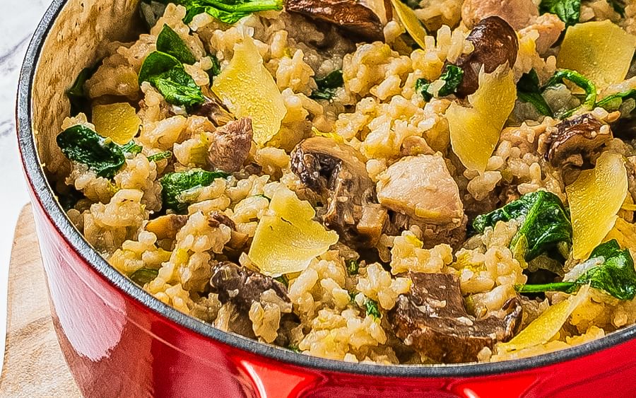 A red oven-proof pot containing a chicken and mushroom risotto