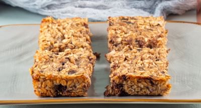 Two servings of the Date Muesli Slice served on a plate in front of the baking tray.