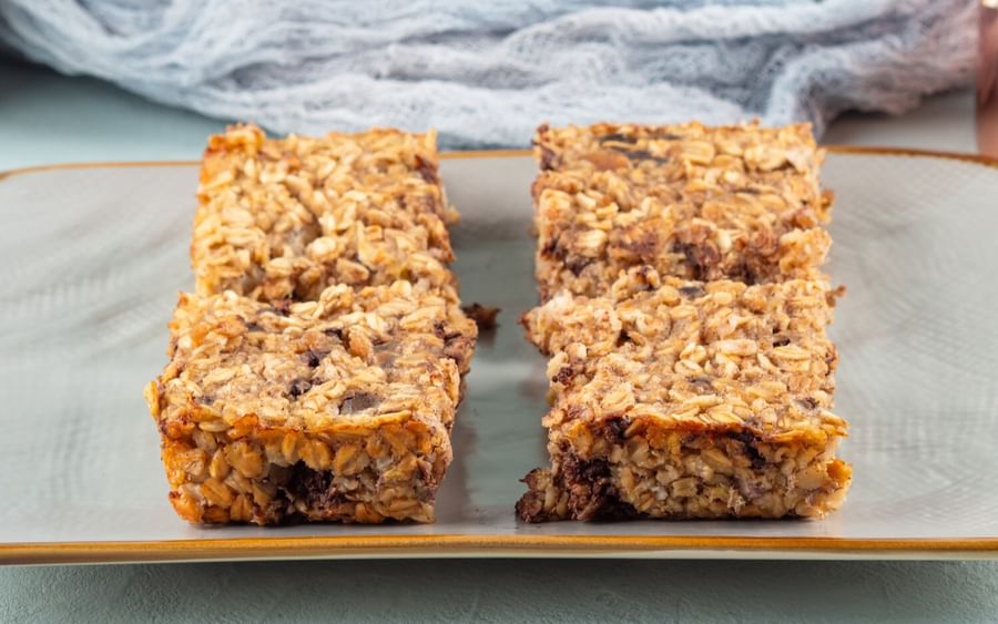 Two servings of the Date Muesli Slice served on a plate in front of the baking tray.