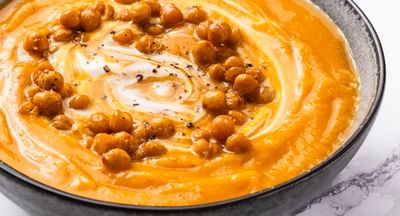 A bowl of pumpkin and chickpea soup with crispy croutons