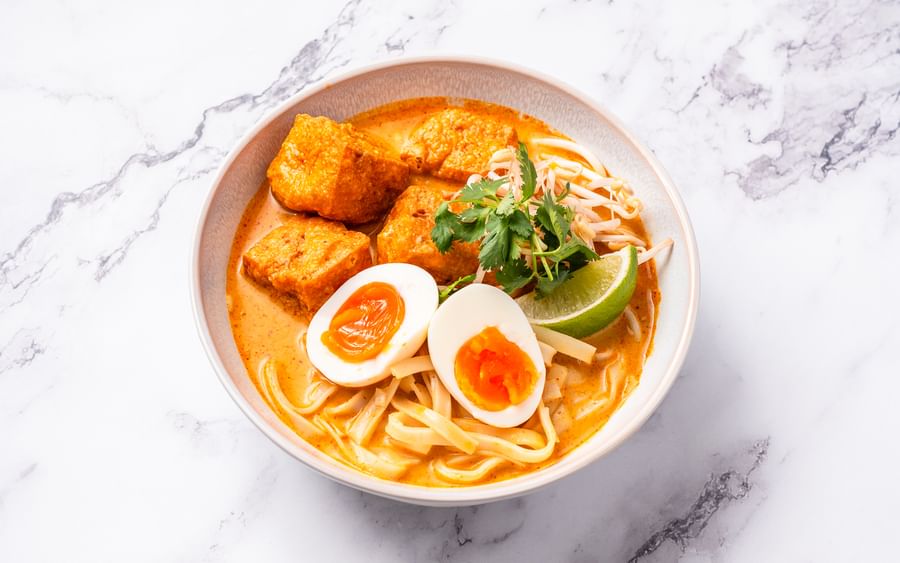 A bowl of tofu laksa with soft-boiled eggs