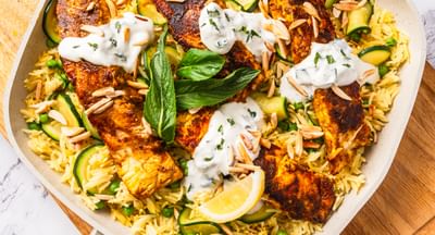 A one-pan tikka masala fish in a wide pan on a chopping board