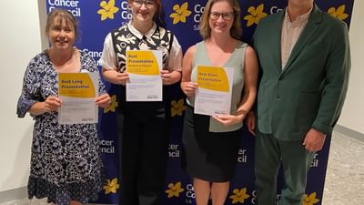 Four people stand in front of a Cancer Council SA backdrop, holding award certificates.
