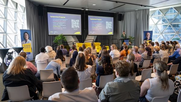 Looking over the back of a group of about 50 people sitting listening to Cancer Council SA's General Manger of Research and Support, Peter Diamond, speak at the podium.