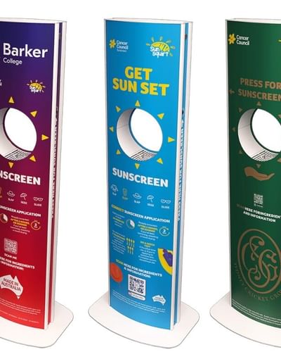 Tall freestanding sunscreen display with purple top and red lower panels on a white base.