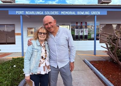 A woman and a man hug in front of the Port Noarlunga Bowling Club main entrance