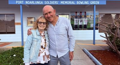 A woman and a man hug in front of the Port Noarlunga Bowling Club main entrance