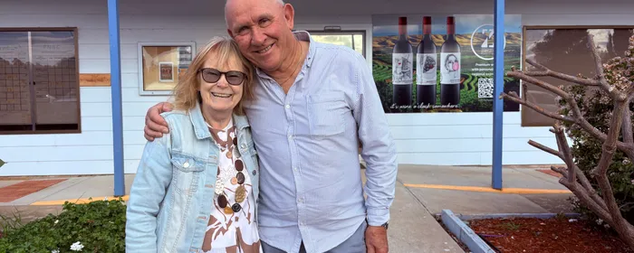 A woman and a man hug in front of the Port Noarlunga Bowling Club main entrance