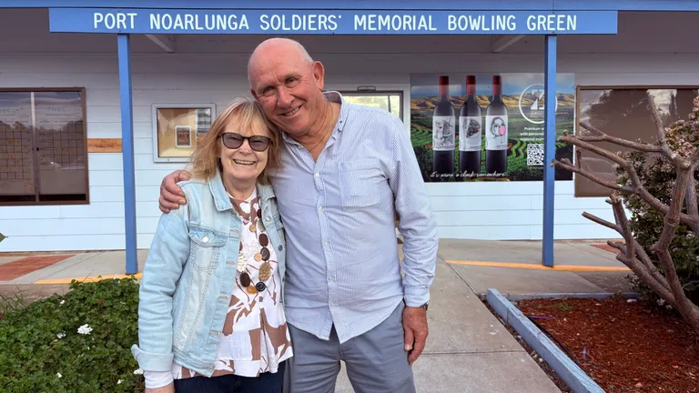 A woman and a man hug in front of the Port Noarlunga Bowling Club main entrance