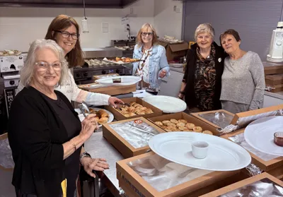 A group of people prepare trays of food in a busy kitchen