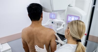 Doctor performing mammography examination testing for breast cancer on male patient in clinic