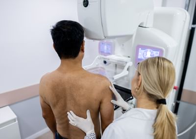 Doctor performing mammography examination testing for breast cancer on male patient in clinic