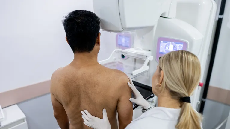 Doctor performing mammography examination testing for breast cancer on male patient in clinic